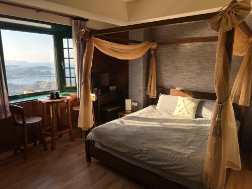 a bedroom with a bed and a desk and a window at Jing Zhan in Jiufen