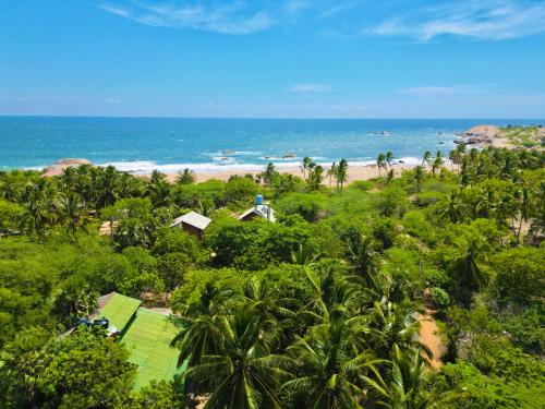 an aerial view of a beach with palm trees and the ocean at Sarada Beach Resort in Tissamaharama