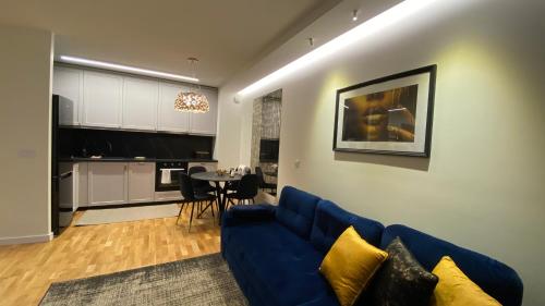 a living room with a blue couch and a table at Lenki apartamenty Białołęka in Warsaw