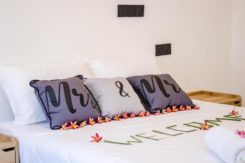 Una cama con almohadas moradas y blancas y flores. en Ahiva Village, en Isla Fulhadhoo