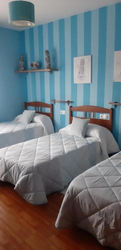 2 camas en una habitación con paredes azules en "O Descanso do Camiño", en Caldas de Reis