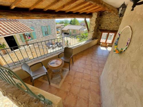 un balcone esterno di una casa con sedie e tavolo di Domaine Saint Claude - Gîte , Chambres d'hôtes & hébergement insolite a Malleval