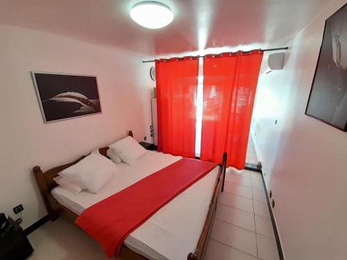 Cette petite chambre comprend un lit avec un rideau rouge. dans l'établissement Studio Village Naturiste Devil or Eden, au Cap d'Agde