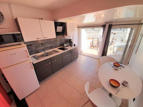 une cuisine avec un réfrigérateur blanc et une table dans l'établissement Studio Village Naturiste Devil or Eden, au Cap d'Agde