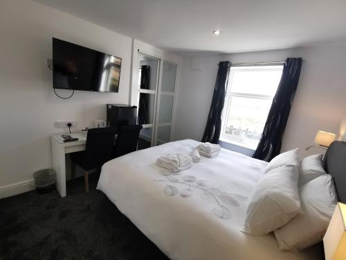 a bedroom with a white bed with a window and a desk at The Kerswell Hotel in Morecambe