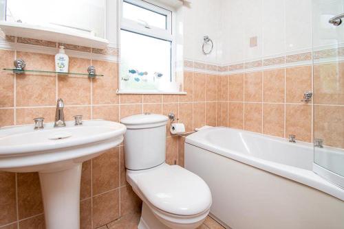 a bathroom with a toilet and a sink and a bath tub at Greenacres in Llanbedrog
