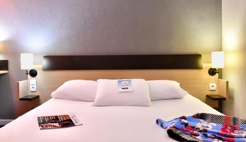 a bedroom with a white bed with two magazines on it at Kyriad Tours Sud - Chambray Lès Tours in Chambray-lès-Tours