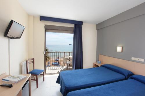 a hotel room with a blue bed and a balcony at Hotel Bilbaino in Benidorm