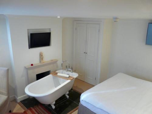 a white bathroom with a bed and a bath tub at Manor Green Cottage in Windsor