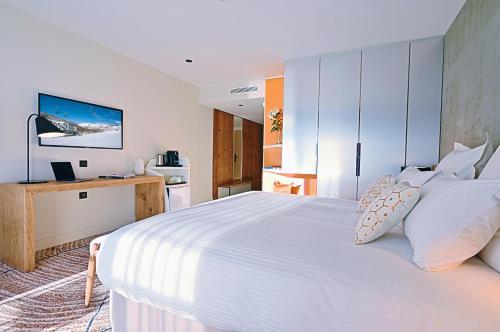 a bedroom with a large white bed and a desk at Hôtel VoulezVous by Les Etincelles in Tignes