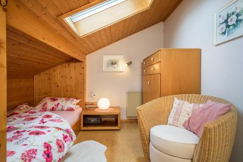 a bedroom with a bed and a chair and a skylight at Haus Sonnenhang Wohnung 3 in Stiefenhofen