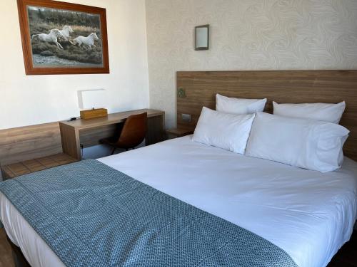 a bedroom with a large bed with a desk and a bed sidx sidx at Hôtel Le Mirage in Saintes-Maries-de-la-Mer