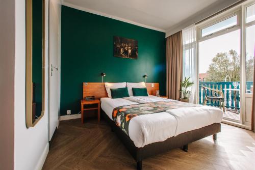 a bedroom with a bed and a green wall at Hotel Keur in Zandvoort