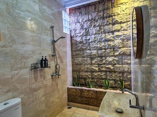 baño con ducha y pared de piedra. en Ndalem Suryo Saptono Guest House en Yogyakarta