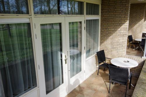 a screened porch with glass doors and a table at Hotel and Restaurant van Saaze in Kraggenburg