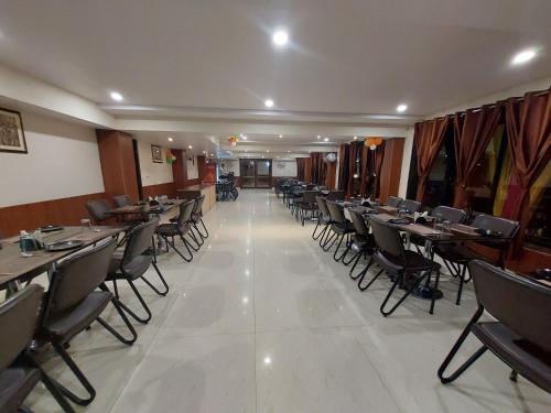 a restaurant with tables and chairs in a room at Hotel Vrinda in Maihar