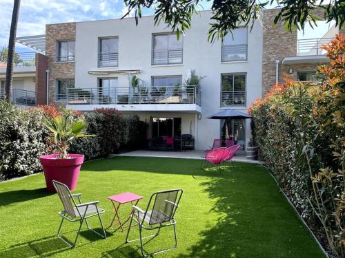 einen Garten mit Stühlen und einem Tisch vor einem Haus in der Unterkunft BLUE DREAM in Juan-les-Pins