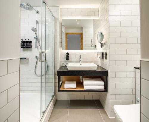 a white bathroom with a sink and a shower at Holiday Inn Manchester Airport, an IHG Hotel in Hale