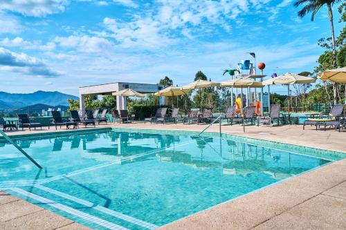 a swimming pool with chairs and umbrellas at a hotel at Monthez Hotel & Eventos in Brusque