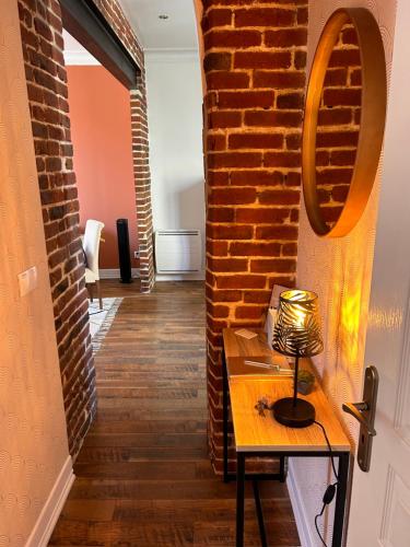 Cette chambre est dotée d'un mur en briques et d'une table avec une lampe. dans l'établissement Appartement chic et cosy, à Épernay
