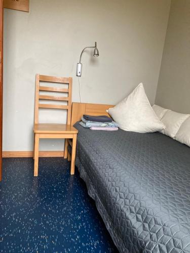 a bedroom with a bed and a chair and a lamp at LELB Rekolekciju centrs Mazirbē in Mazirbe