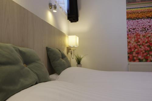 a bedroom with a white bed and a television at Hotel and Restaurant van Saaze in Kraggenburg