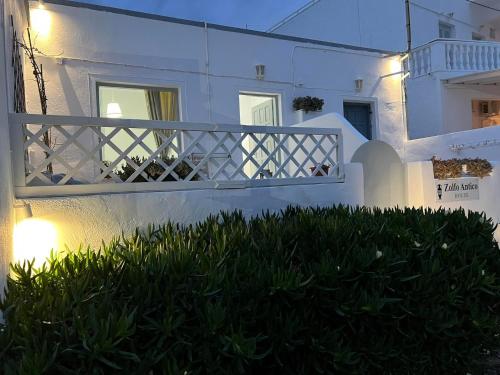 a white building with a balcony and some grass at Zolfo Antico Beach Apartment Perissa in Perissa