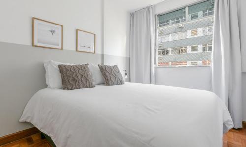 1 cama blanca en un dormitorio blanco con ventana en Tabas Aconchegante apê no Leblon LB0039, en Río de Janeiro