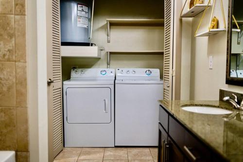 een badkamer met een wasmachine, een droger en een wastafel bij Emerald City Luxury Suite ~Fully Gated Community in Midland