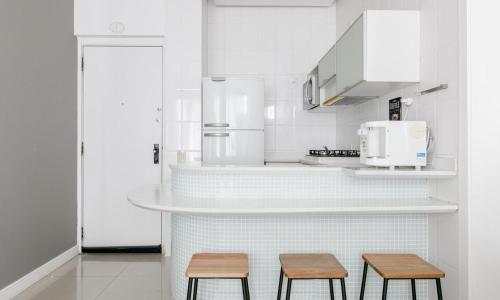uma cozinha com 2 bancos e um balcão com um micro-ondas em Tabas Lindíssimo apê 2 quartos - Leblon LB0045 no Rio de Janeiro