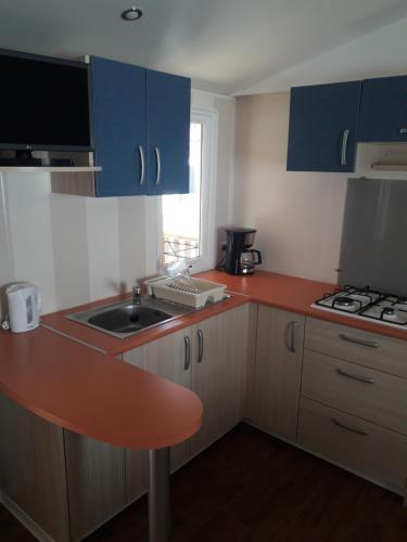 a small kitchen with blue cabinets and a sink at Camping du Lac in Foix