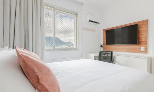 Habitación blanca con cama y TV en Tabas Lindíssimo apê 2 quartos - Leblon LB0045 en Río de Janeiro