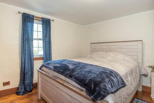 1 dormitorio con 1 cama con cortinas azules y ventana en Peaceful Hollow, en Manchester