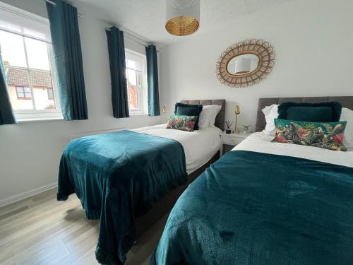 um quarto com 2 camas e um espelho na parede em Kingmaker House! Luxury 4 Beds - Free Private Parking and Garden em Northampton