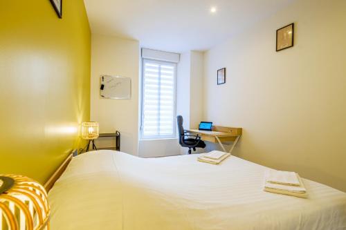 a bedroom with a bed and a desk with a computer at Le 54-GregIMMO-Appart'Hôtel in Belfort
