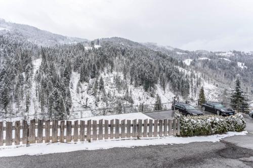 two cars parked in front of a fence in the snow at Chalet Berger in Sankt Johann im Pongau