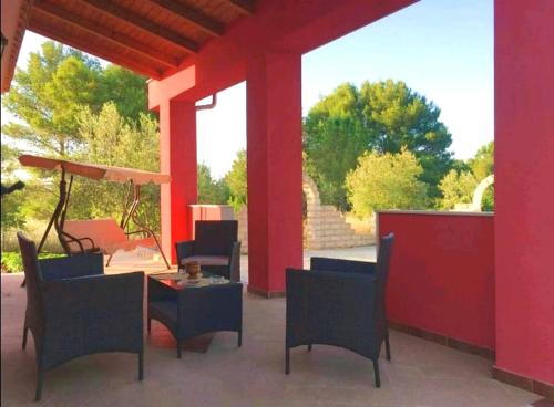 patio con sedie, tavolo e parete rossa di 3 bedrooms villa with private pool enclosed garden and wifi at Noto a Noto