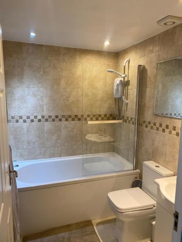 a bathroom with a tub and a toilet and a sink at Kingmaker House! Luxury 4 Beds - Free Private Parking and Garden in Northampton