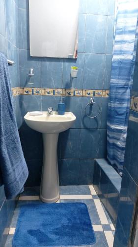 a blue tiled bathroom with a sink and a mirror at Departamento en Cajamarca in Cajamarca