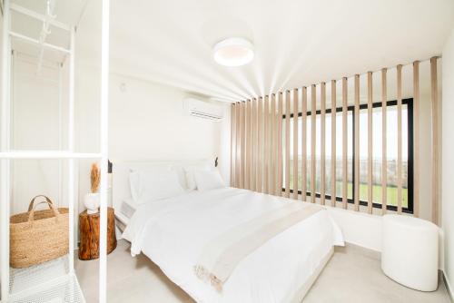a white bedroom with a large bed and a window at Serene seafront villas in Nea Iraklia