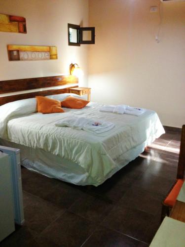 a bedroom with a bed with white sheets and orange pillows at Apart Entrepiedras in Merlo