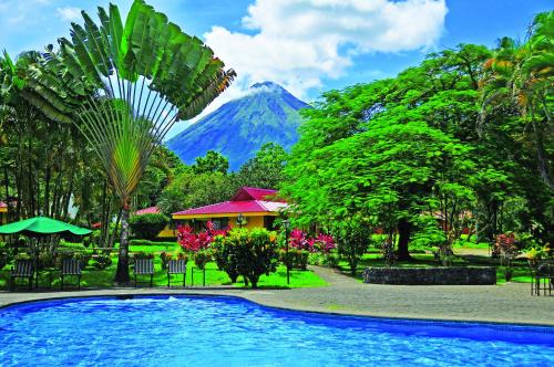 a resort swimming pool with a mountain in the background at Hotel Arenal Country Inn in Fortuna