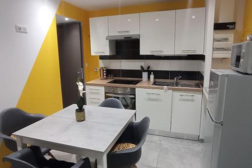 a kitchen with white cabinets and a table with chairs at F1 idéalement situé en RDC in Raon-lʼÉtape