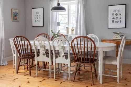 a dining room with a white table and chairs at Bergs Gård & Hållsvikens Gård in Västerljung