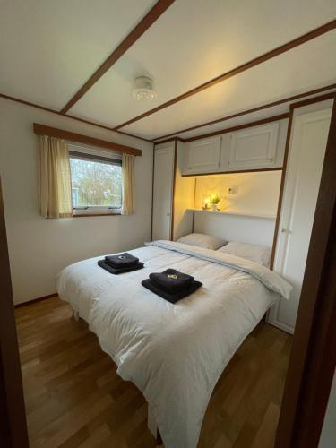 een slaapkamer met een groot wit bed en handdoeken bij Chalet D12 - Camping it Soal in Workum