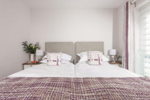 um quarto com uma cama grande com lençóis brancos e almofadas em Wish You Were Here, Crantock em Newquay