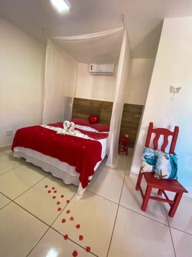 a bedroom with a red bed and a chair at Solar da Praia Pousada in Arraial do Cabo