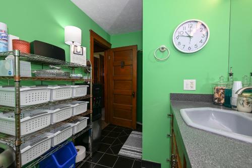 a green bathroom with a sink and a clock on the wall at Berrodin Bed & Breakfast in Akron