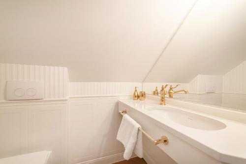 Baño blanco con lavabo y espejo en Pensjonat & Restauracja Admirał, en Jastarnia