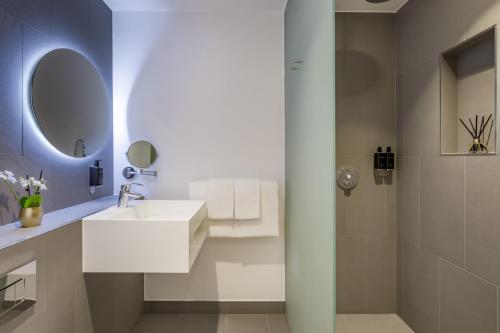 a white bathroom with a sink and a shower at Hotel Indigo London - 1 Leicester Square, an IHG Hotel in London
